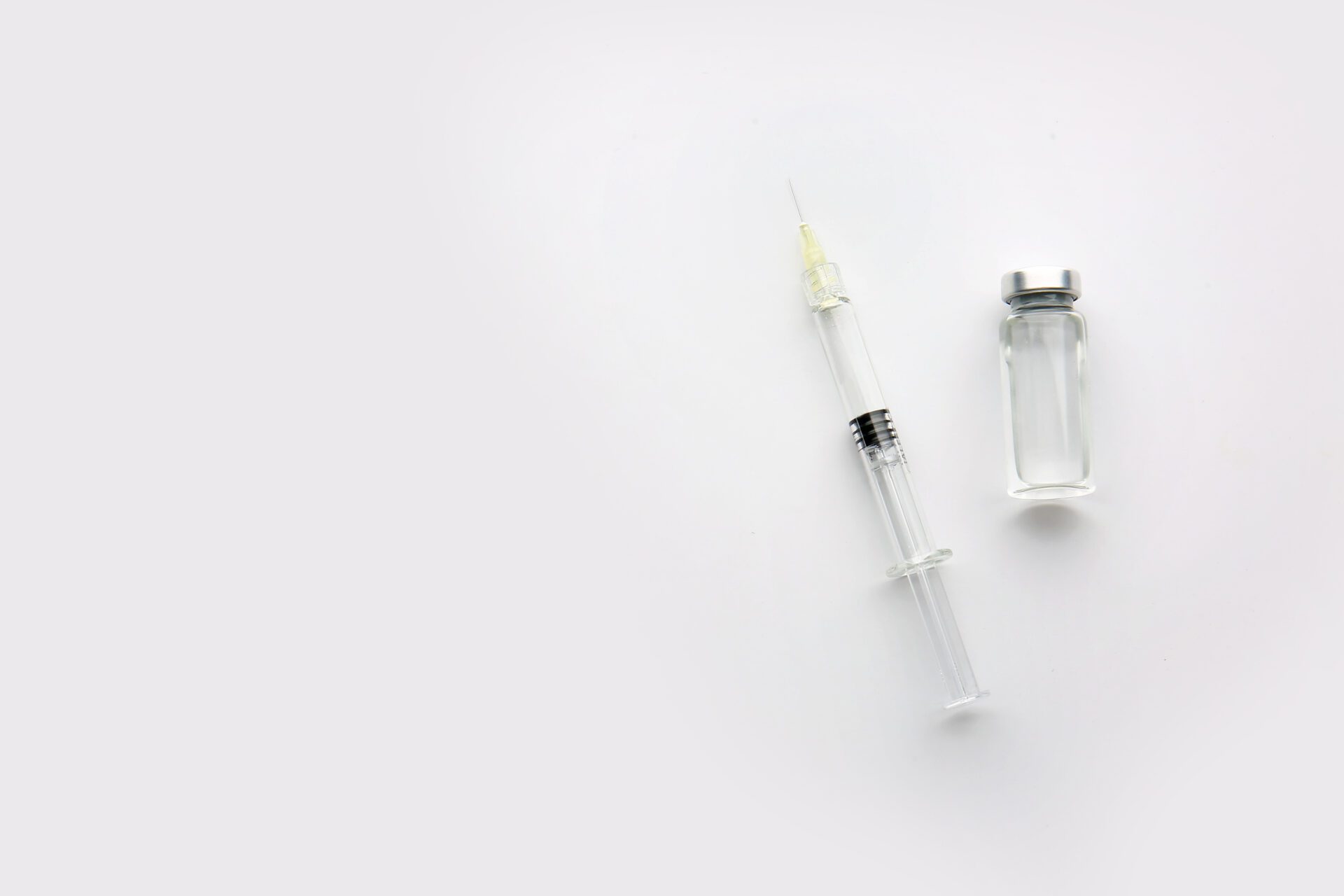 Syringe with filler for cosmetology and ampule on light background